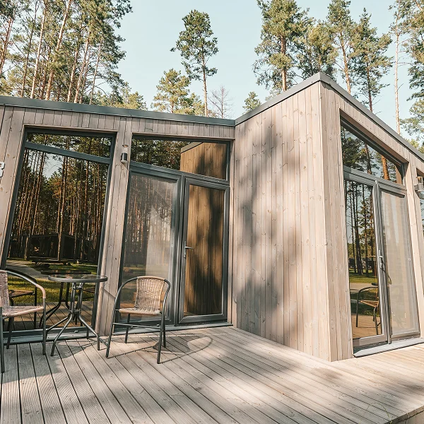 Une cabane en bois avec un patio et des chaises, conçue sur mesure pour un style de vie confortable.